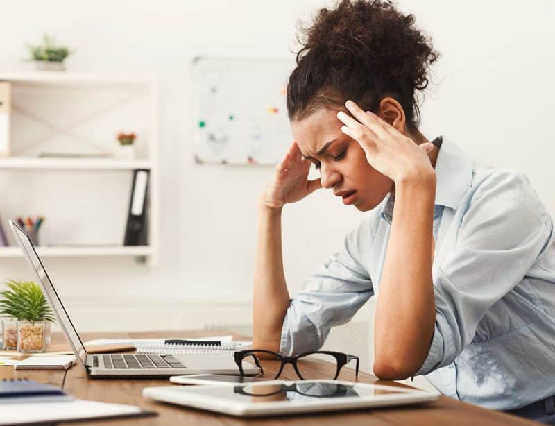 Business woman holding her head in front of her laptop