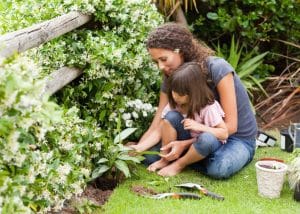 mom gardening with her daughter in lap